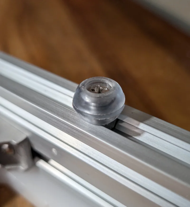 Close-up of a clear silicone foot screwed into the aluminum frame of a DisplayPrep board
